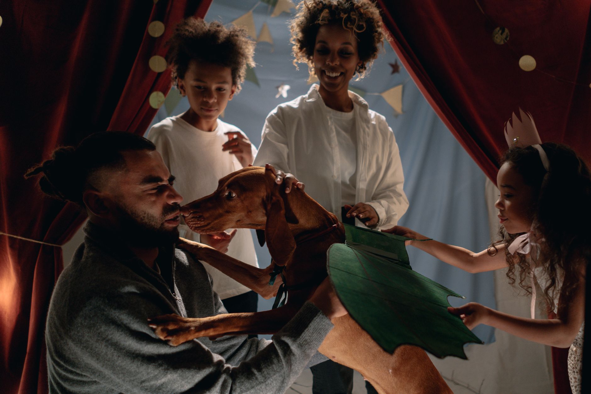 A family enjoys playtime indoors with their pet dog, creating a fun and bonding atmosphere.